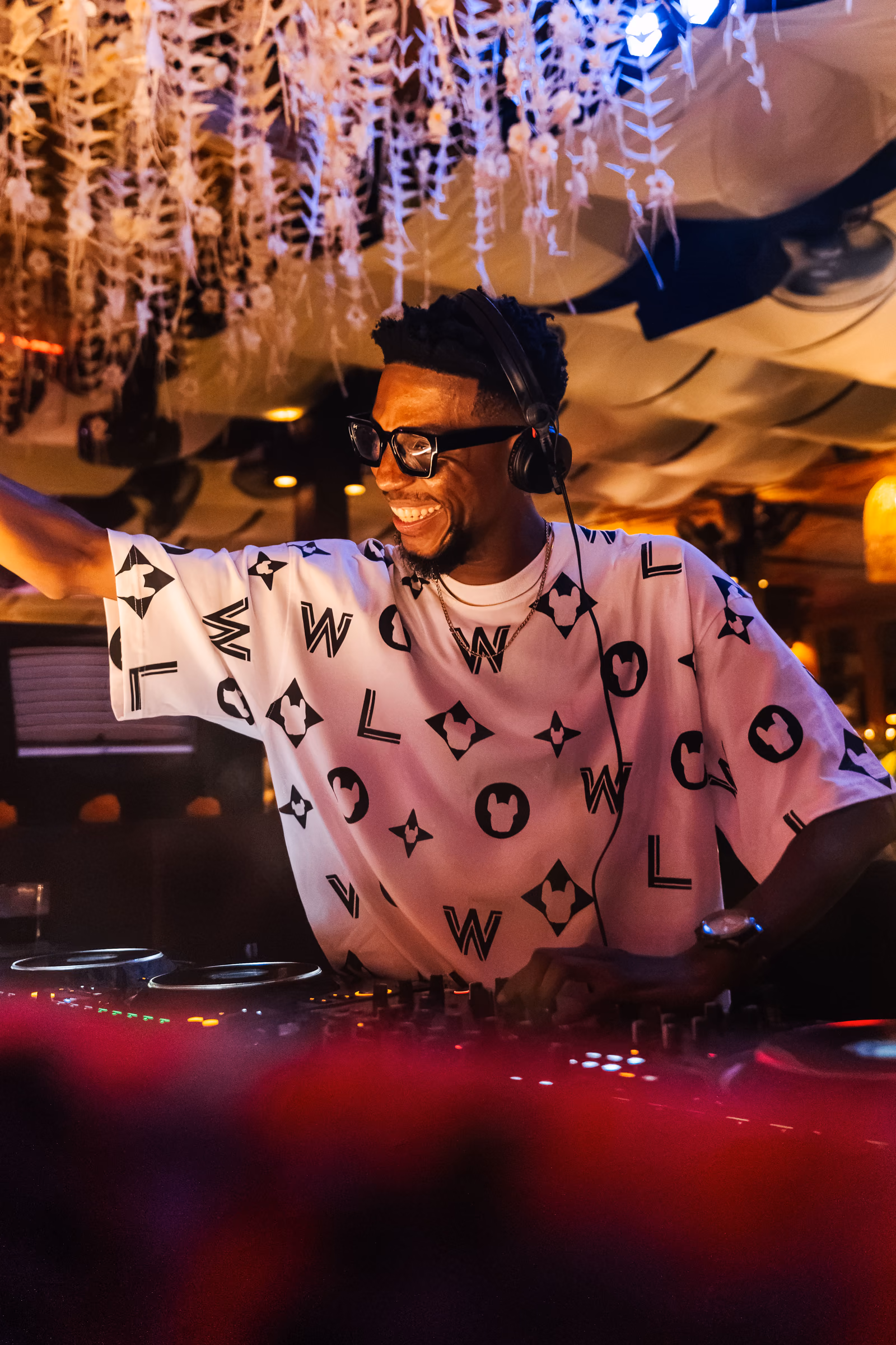 Smiling DJ raising an arm while performing behind the decks