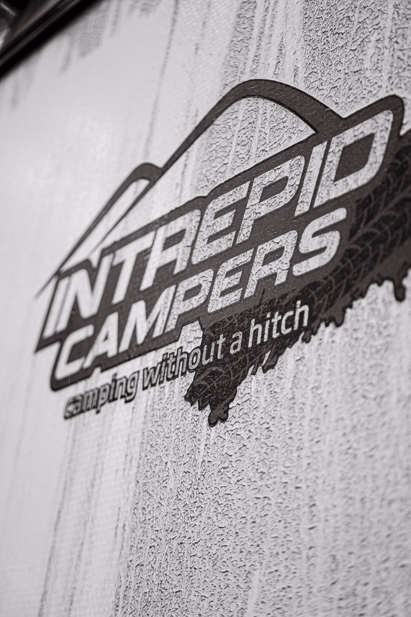 Monochrome close-up of the Intrepid Campers logo