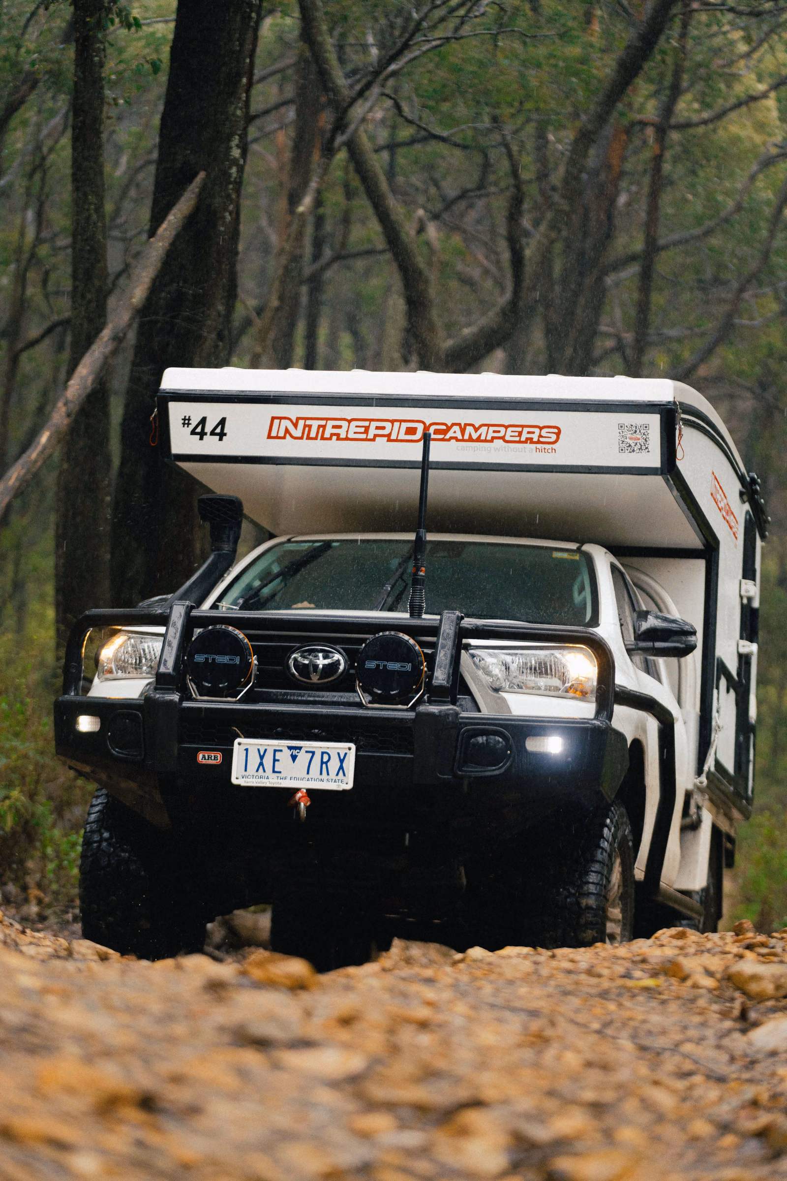 Off-road Toyota camper driving along a rocky forest trail